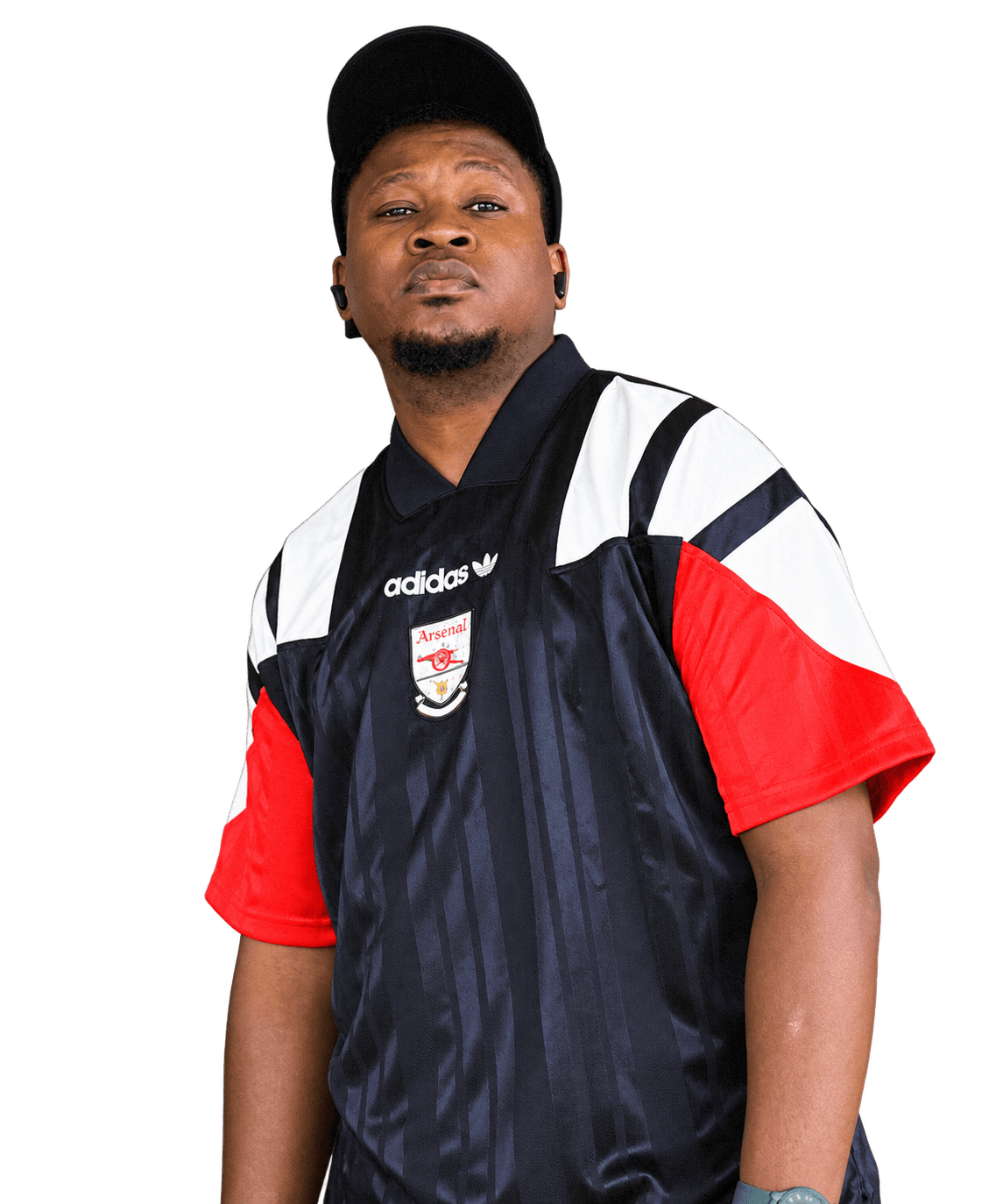 Gift In Oasis in a black cap and a navy, white and red football shirt, looking towards the camera